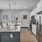 Spacious and well lit kitchen with wood floors and stainless steel appliances. 